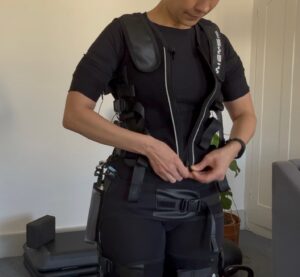 A picture of a woman doing up an EMS training suit